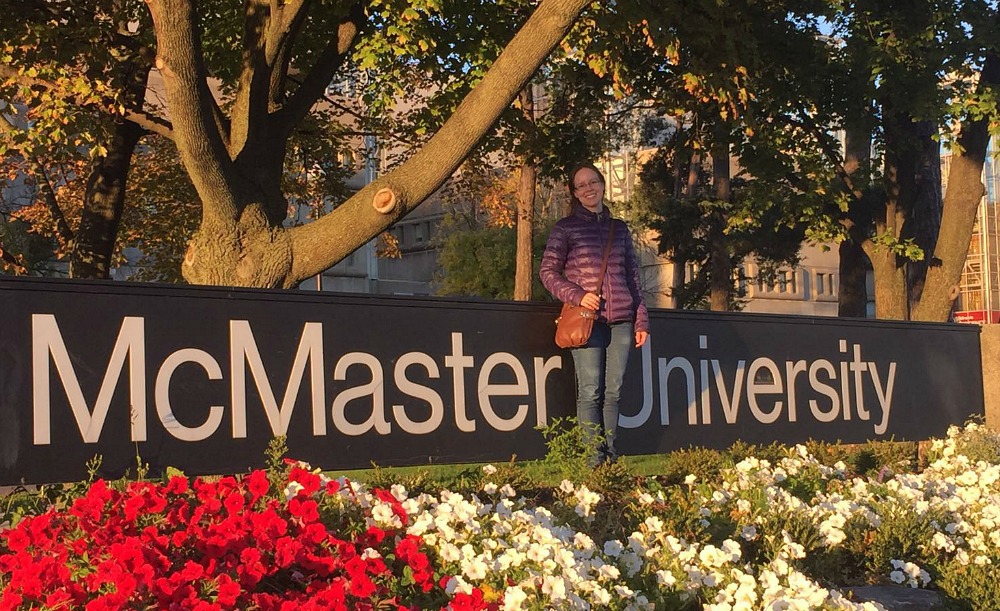 Adriana Nori de Macedo poses with the McMaster sign at the university's Main Street entrance.