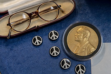 Items from the Russell Archives including his glasses, his Nobel medal, and buttons with the iconic peace sign, the symbol created by the Campaign for Nuclear Disarmament in which Russell was a central figure.