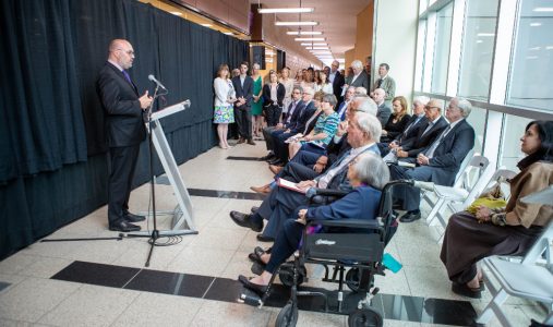 Dr. Gerry Wright standing at a podium in a hallway in front of a black curtain at the opening of the David Braley Centre for Antibiotic Discovery