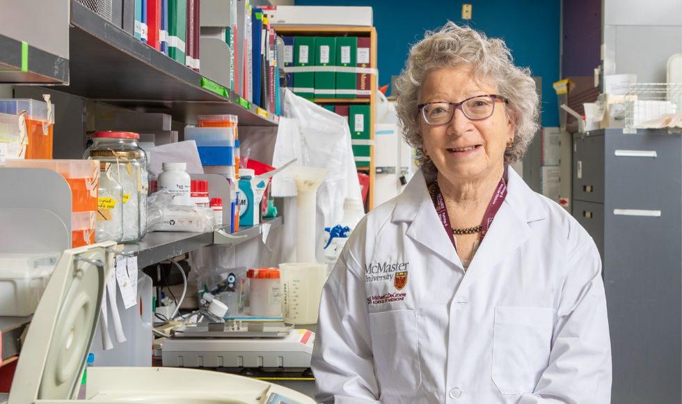 A woman in a lab, smiling, wearing a lab coat