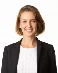 A headshot of Meredith Vanstone. She is wearing a white shirt, black blazer and is smiling at the camera. There is a white backdrop behind her. 