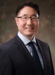 Headshot of a smiling man in a suit and tie