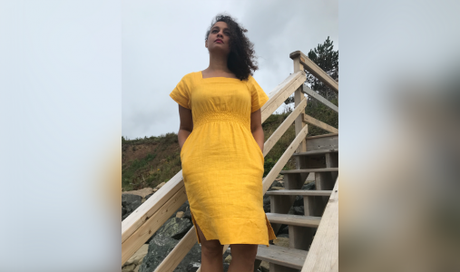 Keena Trowell standing on an outdoor staircase in a yellow dress