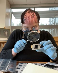 Kaci Switzer looks at a photo negative through a magnifying glass.