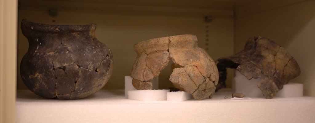 Three reconstructed archaeological cooking vessels on a shelf 