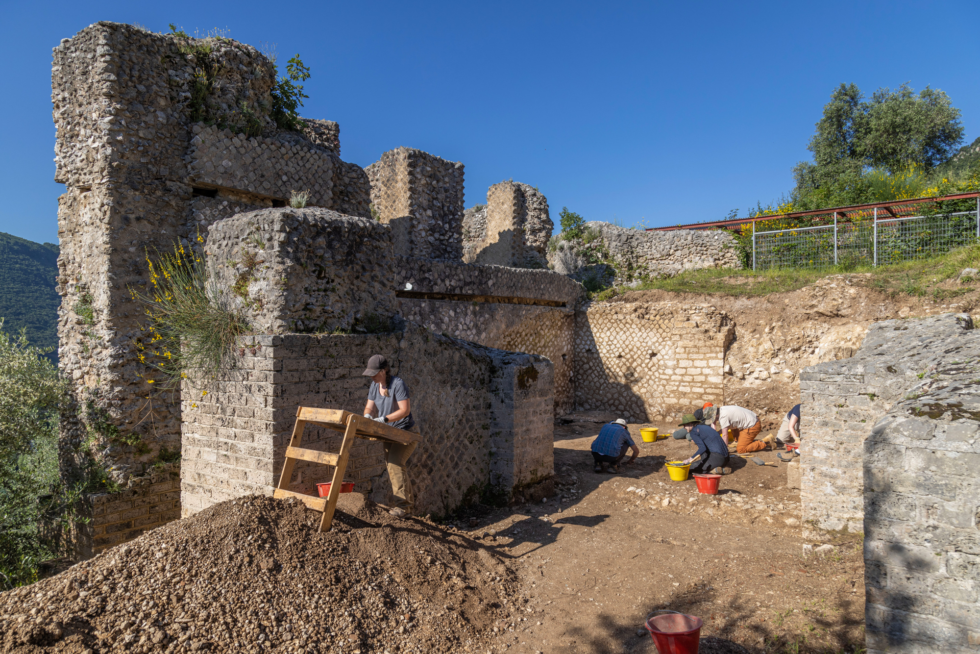 A group of students and researchers engaged in an active archaeological dig at Villa di Tito.