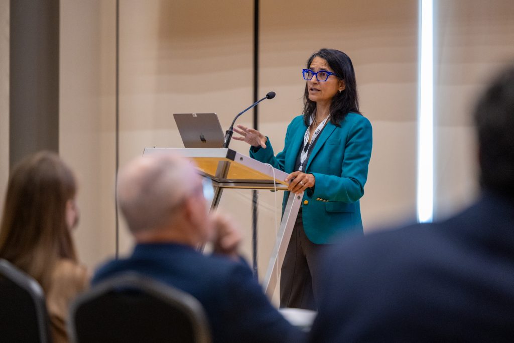 Sonia Anand speaking at a podium 