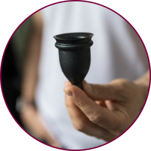 A hand holding a black silicone menstrual cup 
