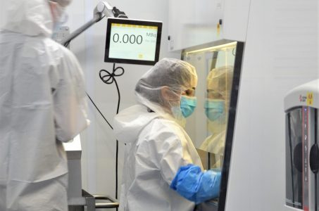 A person in a biohazard suit with gloves and a mask in a laboratory