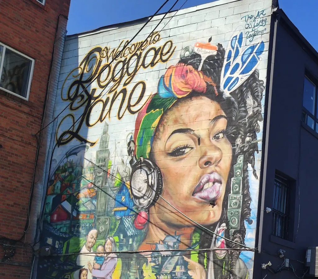 Image of a Mural of a lady with headphones on that says "reggae lane"