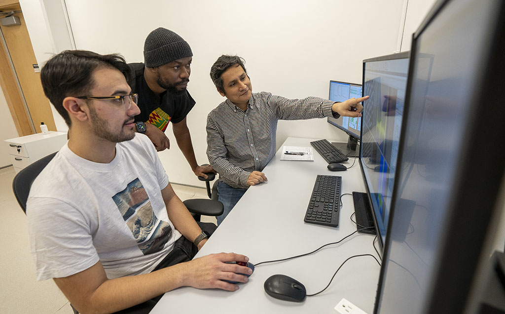 PhD students Babafemi Agboola (centre) and Joaquin Eduardo Reyes Gonzalez (left) analyzing data from the Nion HERMES 100 with Professor Maureen Joel Lagos (right).