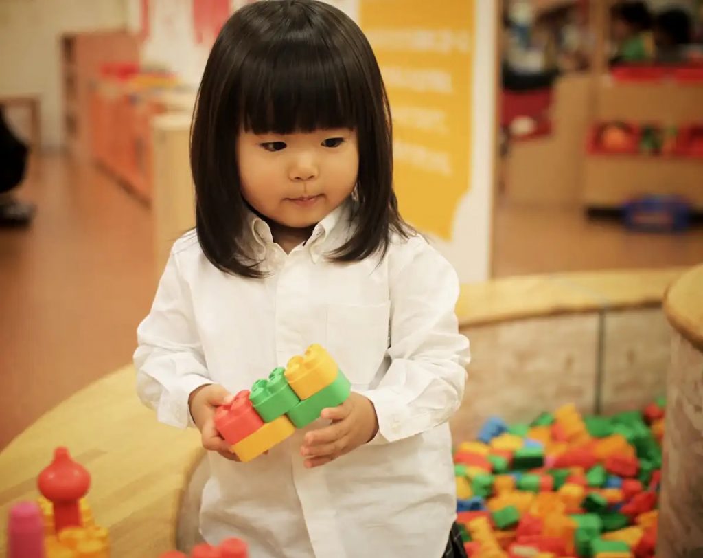 Image of a little girl holding her building blocks 