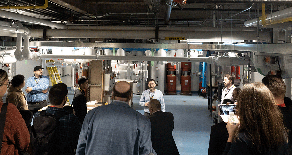 A man speaking to a crowd of people gathered in a laboratory 