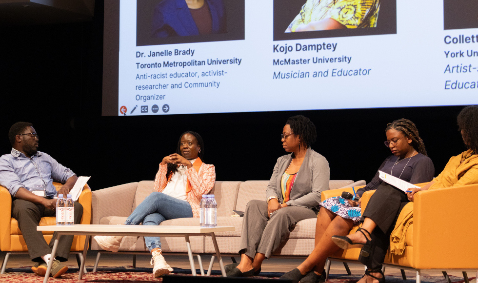 Five people in discussion while seated on a stage