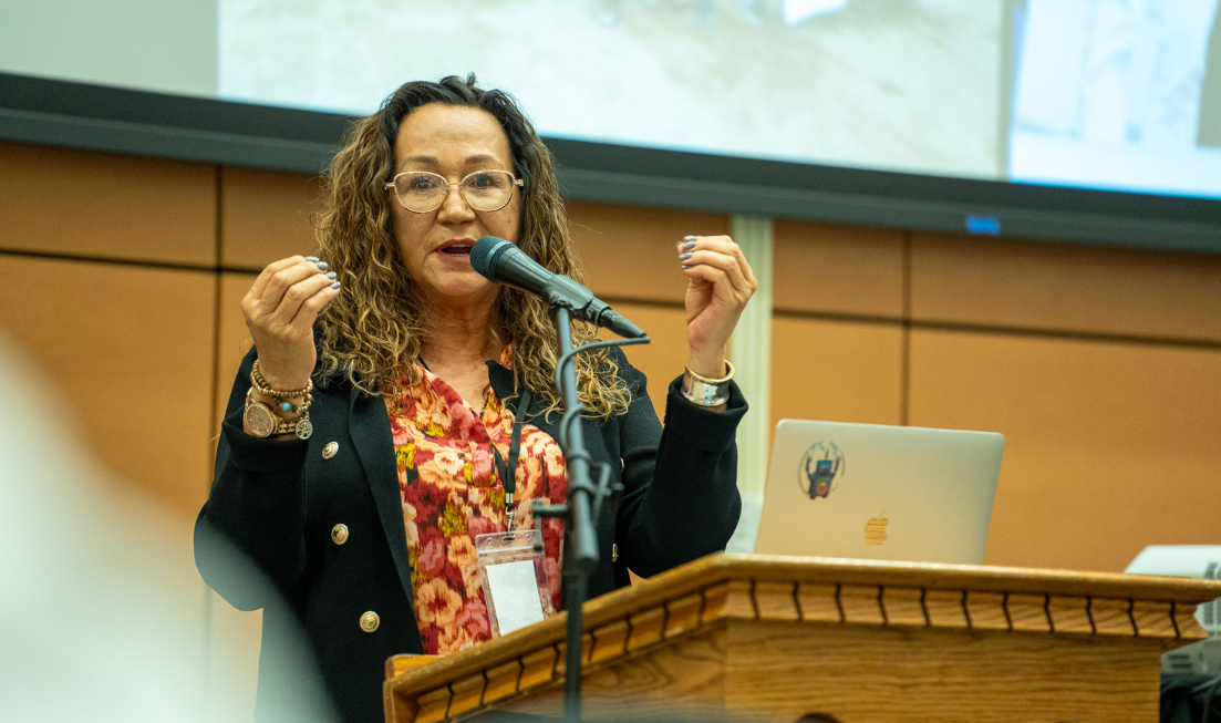 Dawn Martin-Hill gestures with both hands while speaking at a podium