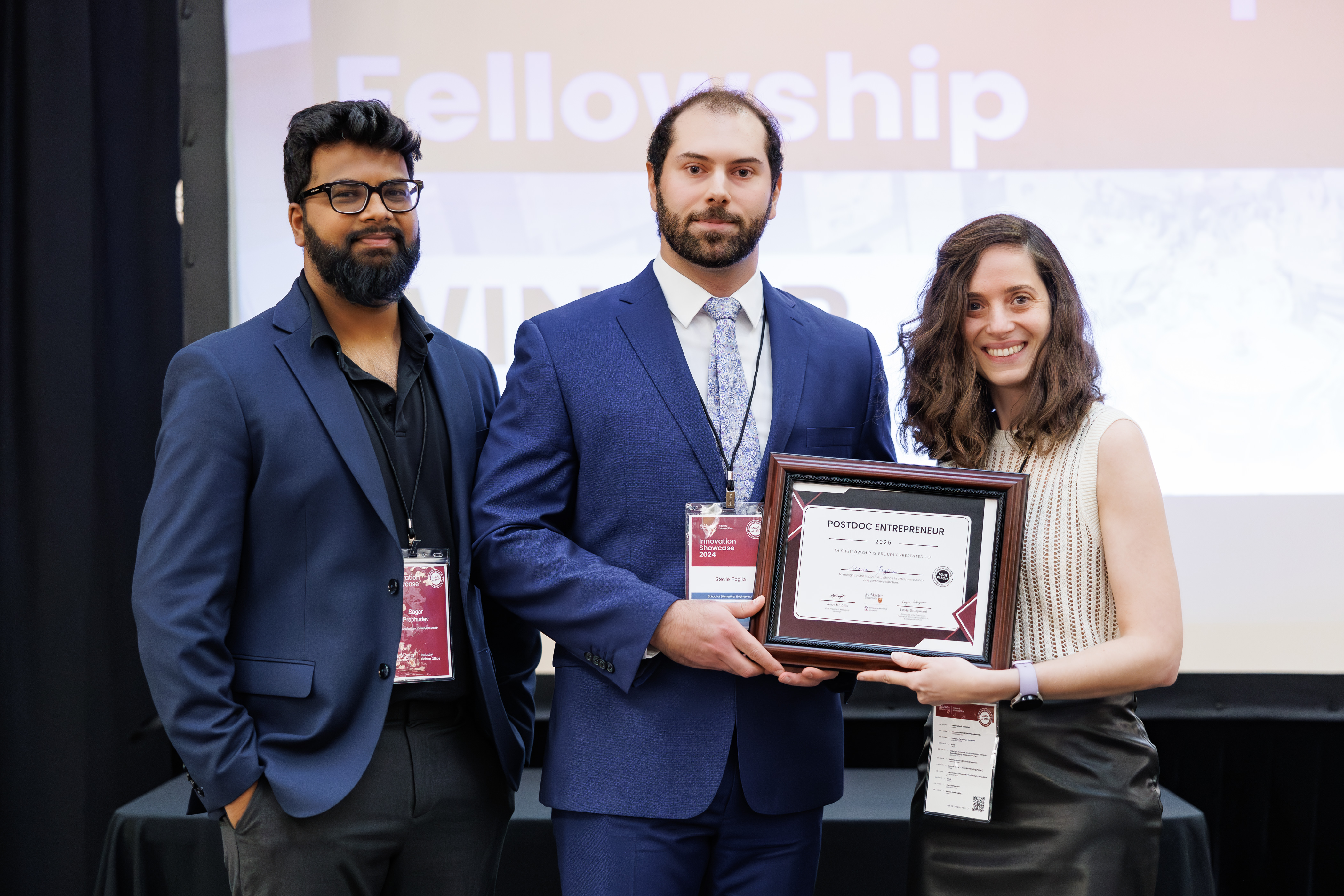 Sagar Prabhudev stands beside Steve Foglia as Leyla Soleymani hands Foglia a framed plaque commemmorating his new fellowship.