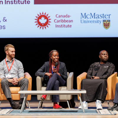 Five student researchers sit in a row of armchairs on stage during a panel discussion.
