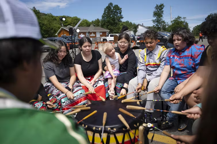 People sit drumming in a circle.