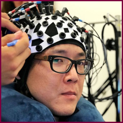 A headshot of Gabriel Xiao, wearing a helmet with many plugs on it.