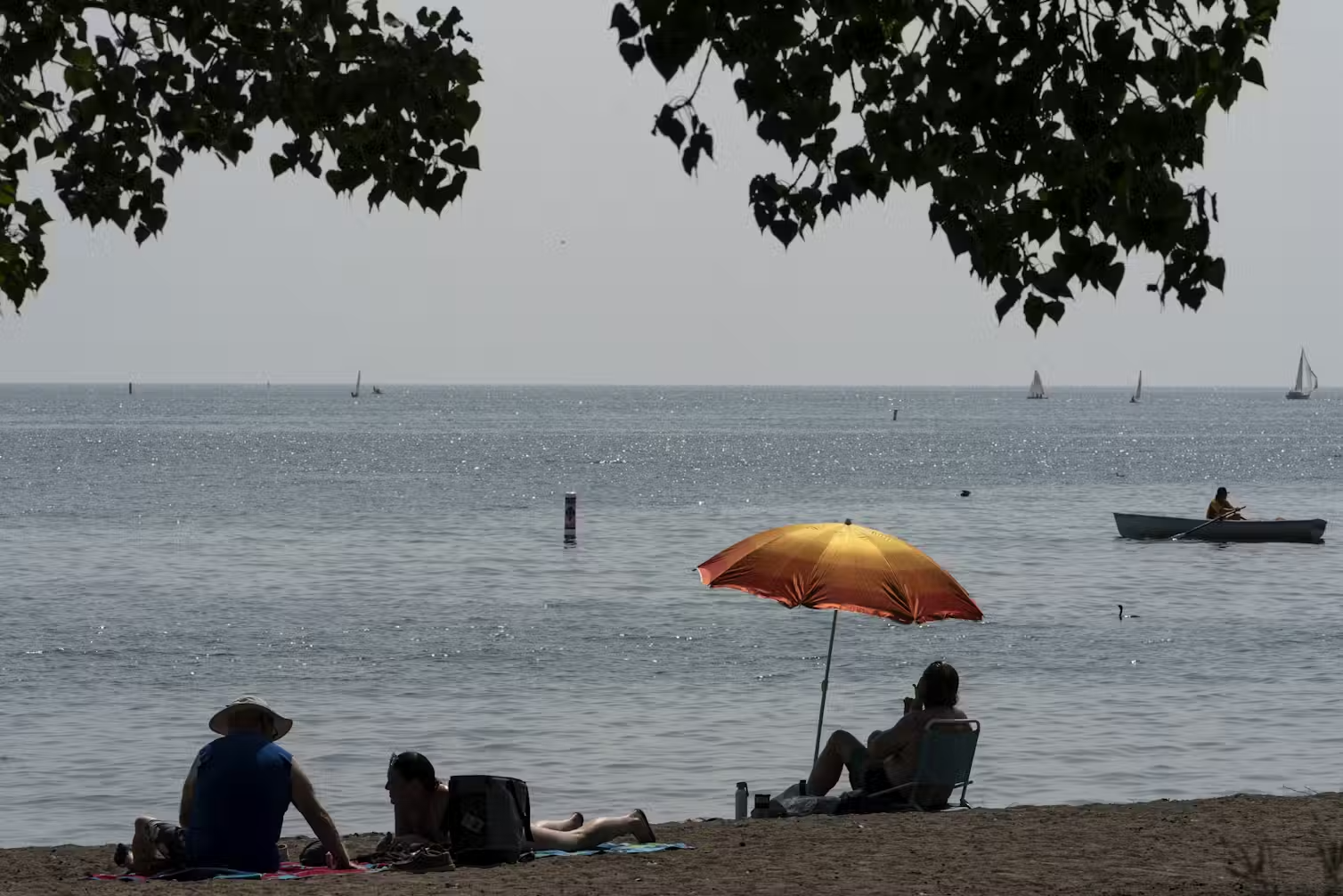 People sit by an umbrella on the beach.