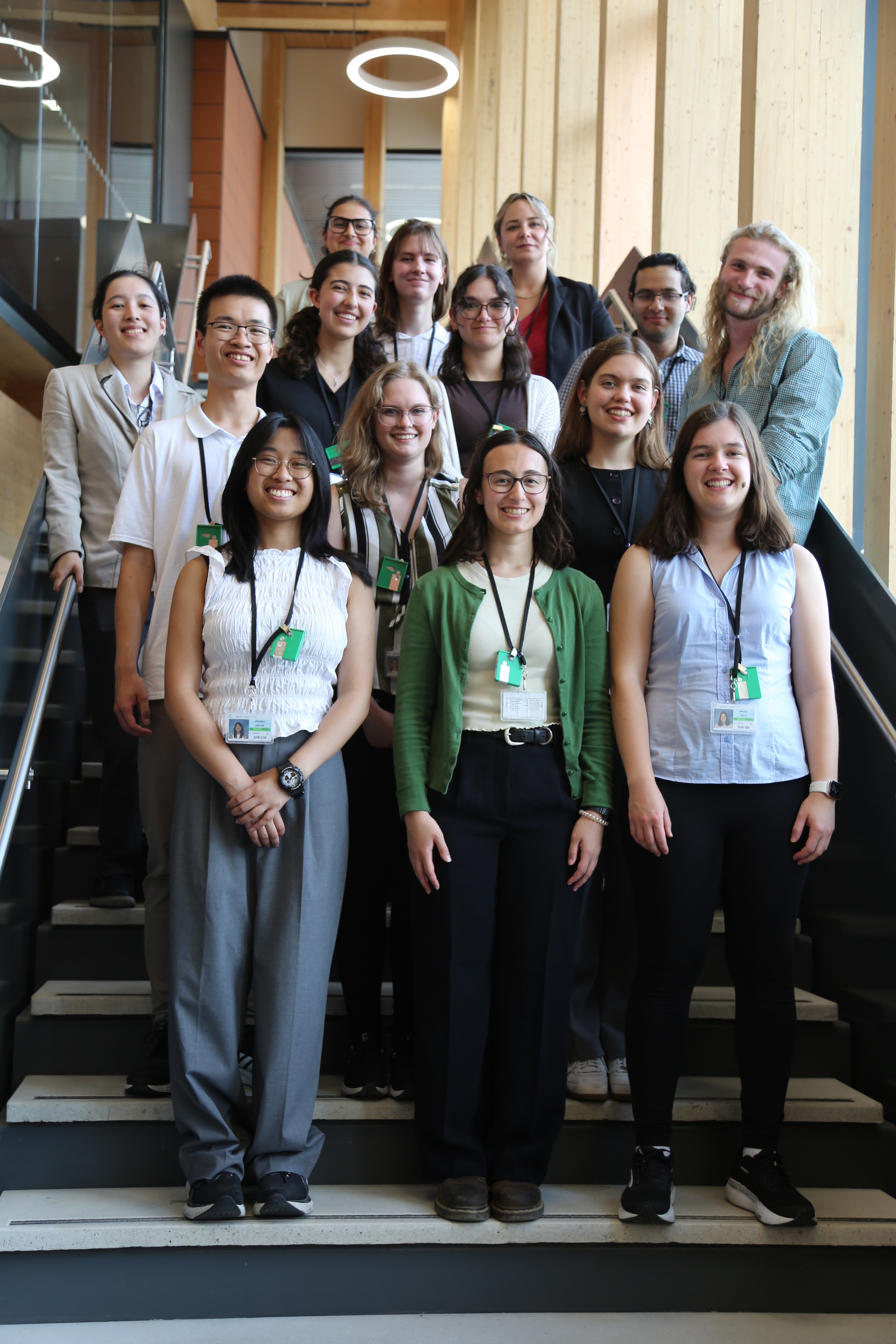 A group shot of fifteen people standing in rows on a staircase.