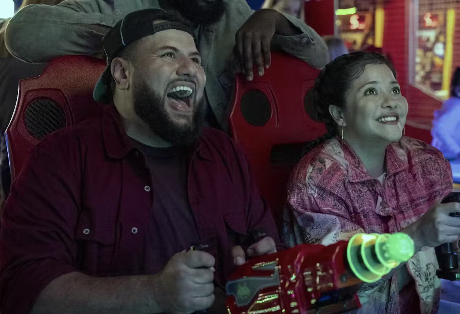 Two people laugh as they play an arcade game. 