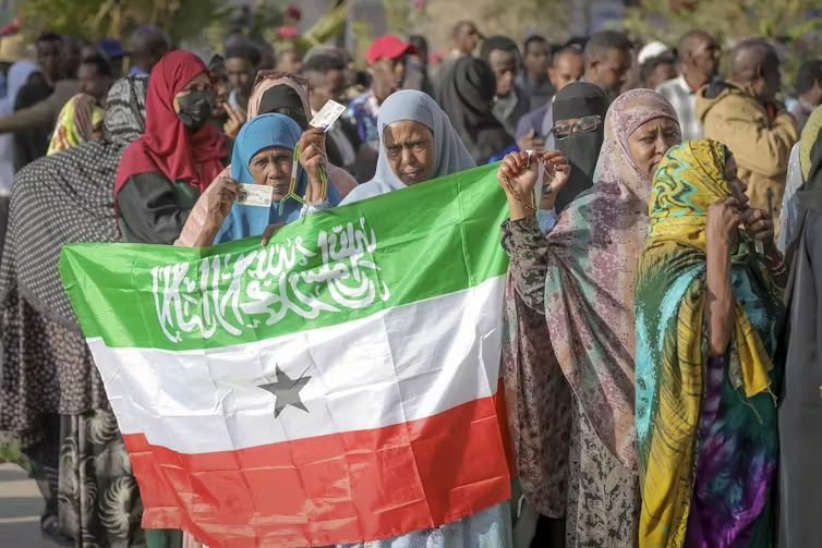 Along the side of a crowd, a woman holds up a Somaliland flag.