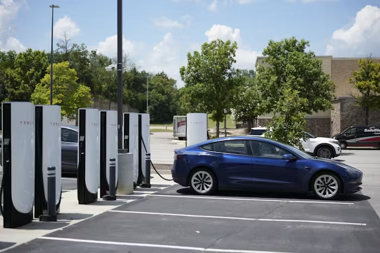 A Tesla electronic vehicle is parked a charging station. 
