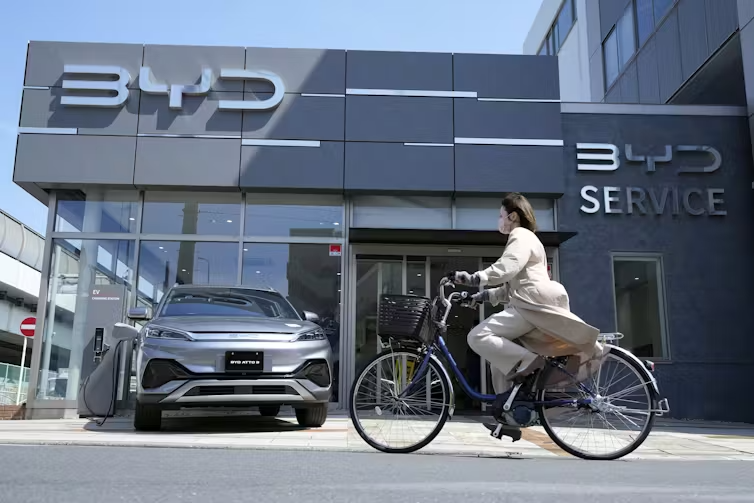 A woman rides a bicycle past a BWD building. 