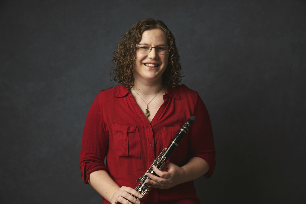 Photo of McMaster engineering student Larissa Taylor in a red shirt holding a clarinet