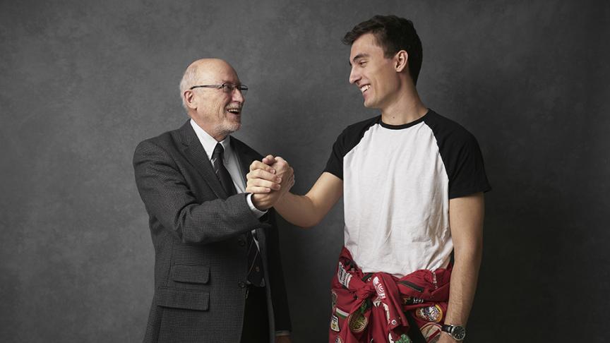 One older man and one younger man clasp hands