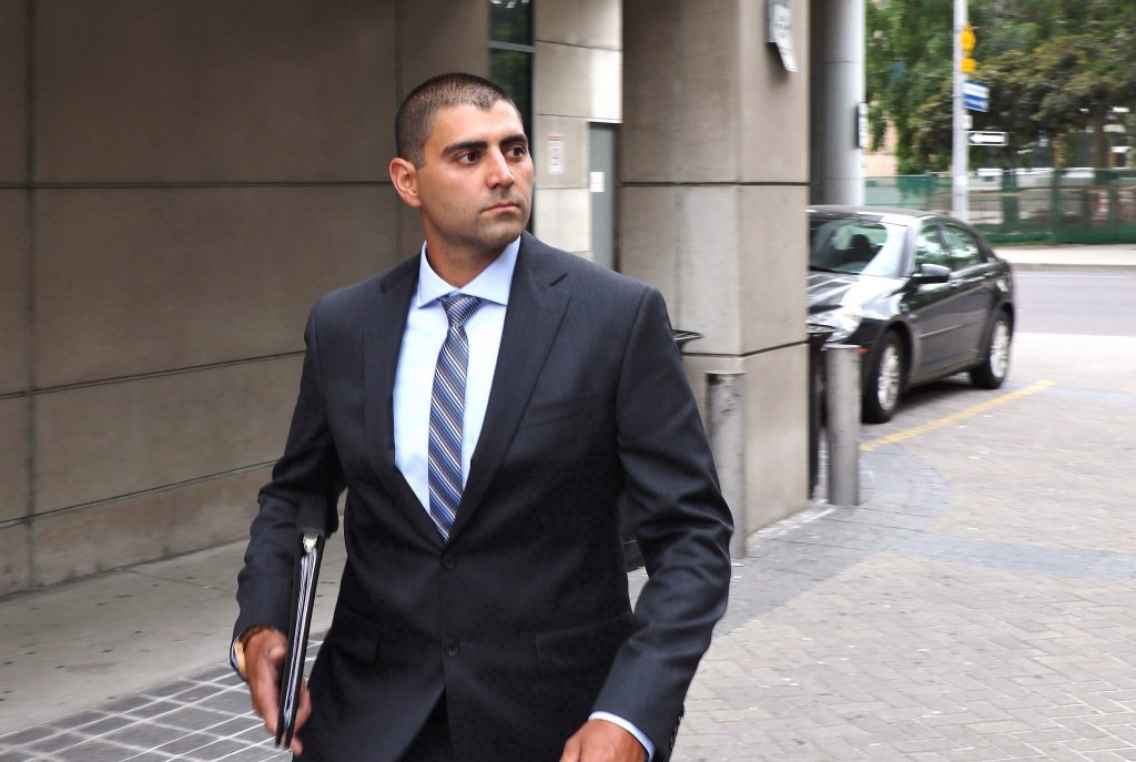 a mAN IN A BUSINESS SUIT STANDS OUTSIDE A COURTHOUSE