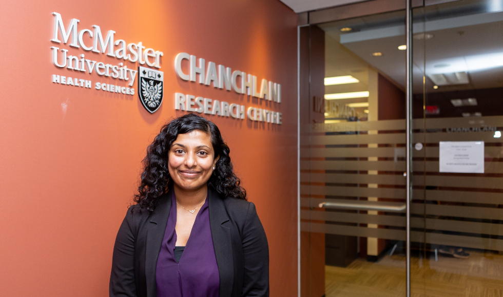 A South Asian woman stands outside the Chanchlan Research Centre at McMaster University