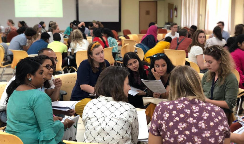 Groups of students sitting around tables during a symposium