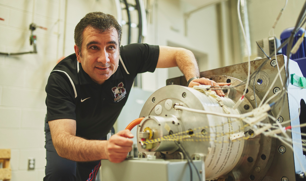 Engineering Professor Ali Emadi is working on something mechanical on a tabletop.