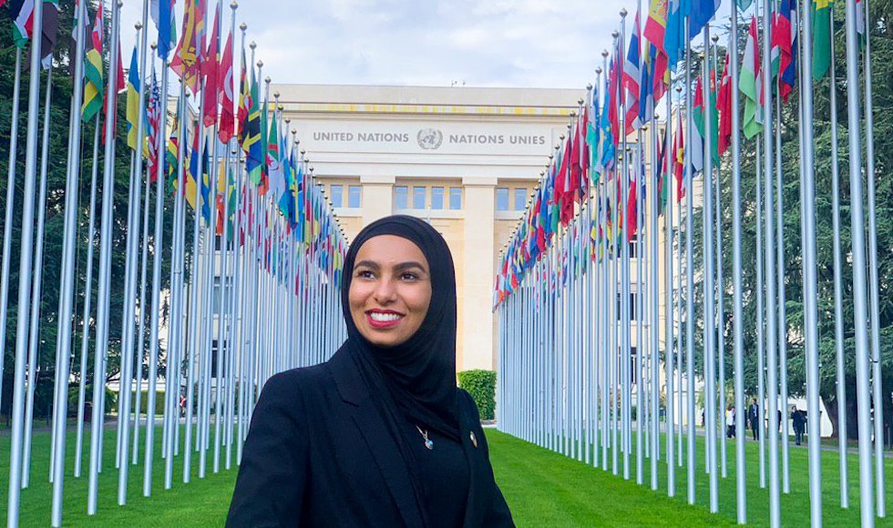 A woman in a hijab stands in front of the United Nations