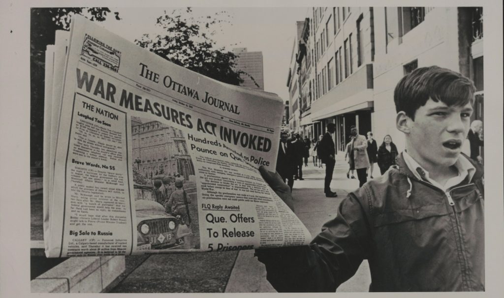 archival photo of a paper boy holding up a newspaper that says 