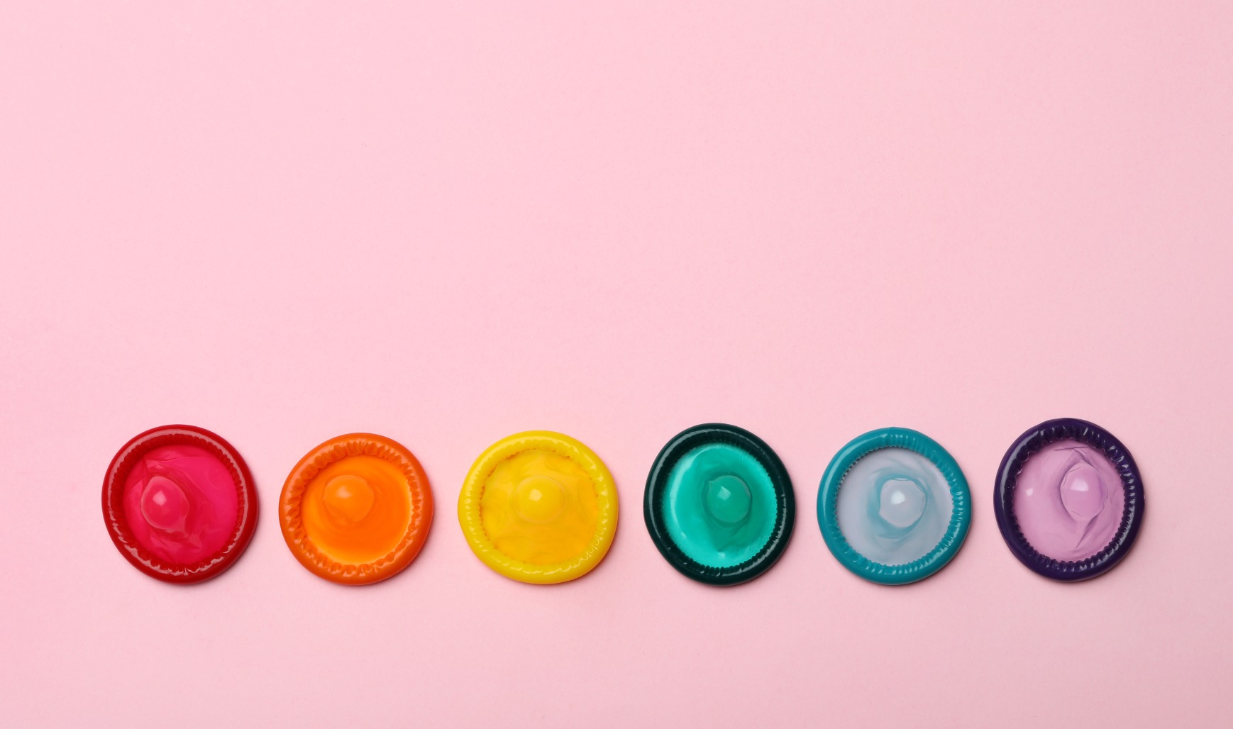 Coloured condoms arranged in a rainbow.