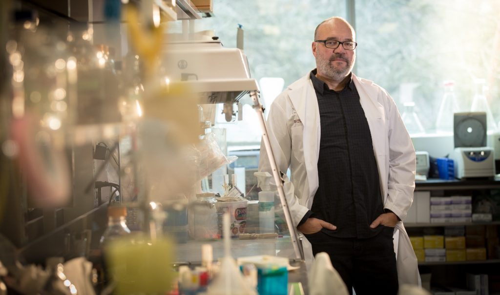 Gerry Wright in a lab full of scientific equipment, wearing a lab coat.