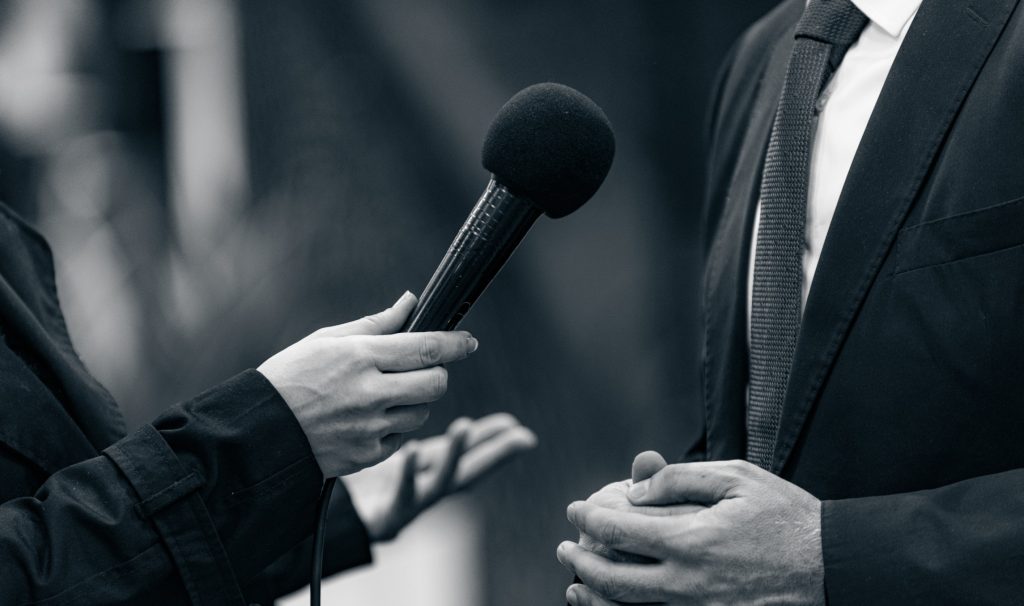 Hands holding a broadcast microphone close to another person