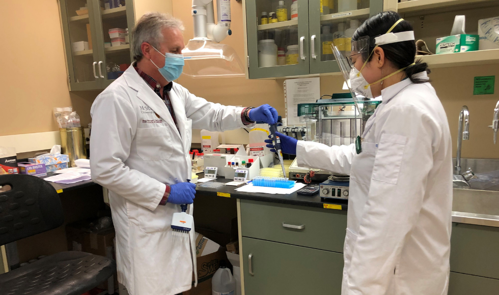 Two technicians wearing lab coats and masks work in McMaster's Platelet Immunology Laboratory.