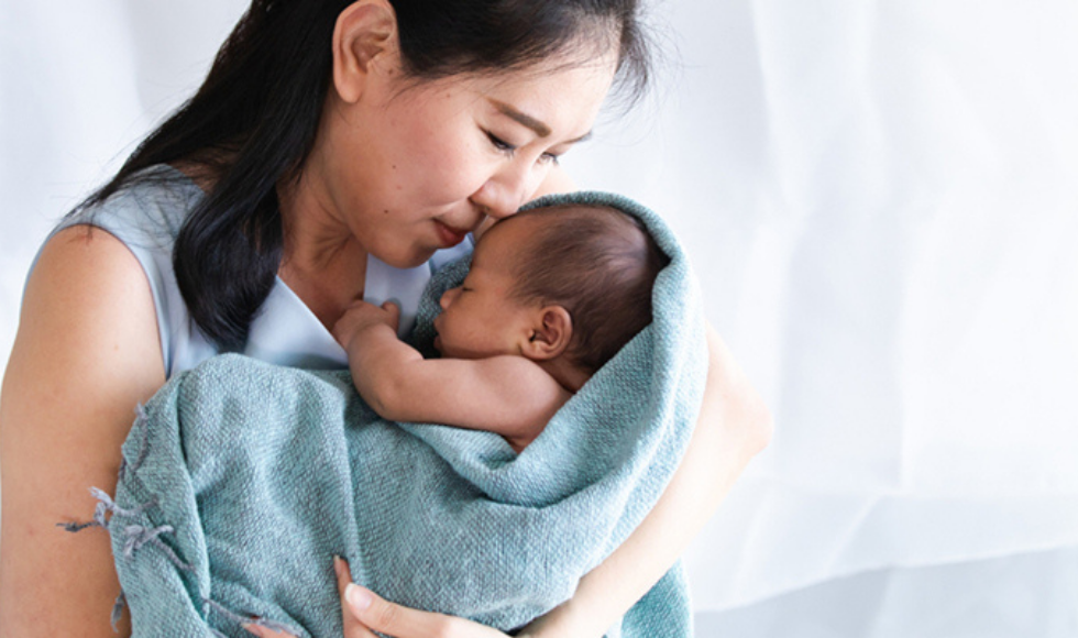 A woman hugs a baby wrapped in a blanket