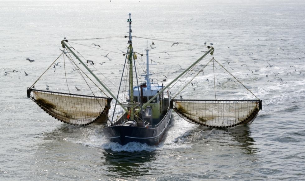 A commercial fishing boat with huge nets extended on either side of it.