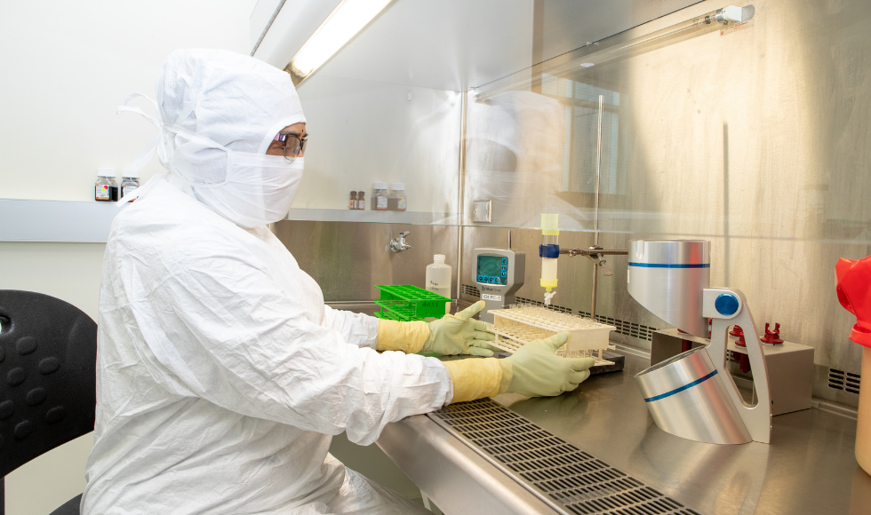 lab worker, fully masked, works on preparing a vaccine.