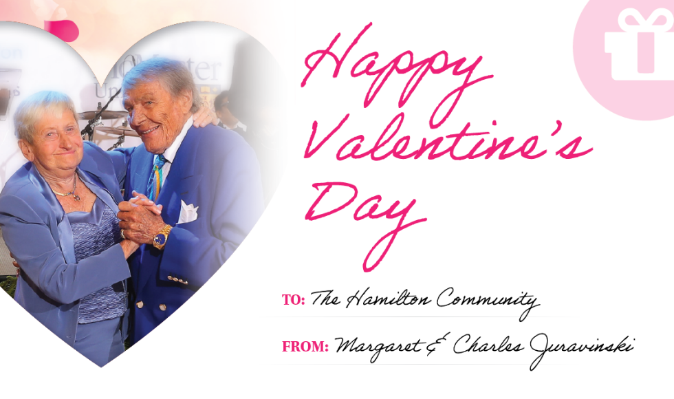 The graphic is a Valentine’s Day card. The top reads, “Happy Valentine’s Day.” The card is addressed to “The Hamilton Community” from “Margaret and Charles Juravinski.” On the left is a photo of Margaret and Charles inside the shape of a heart. The top right includes an icon of a gift box.