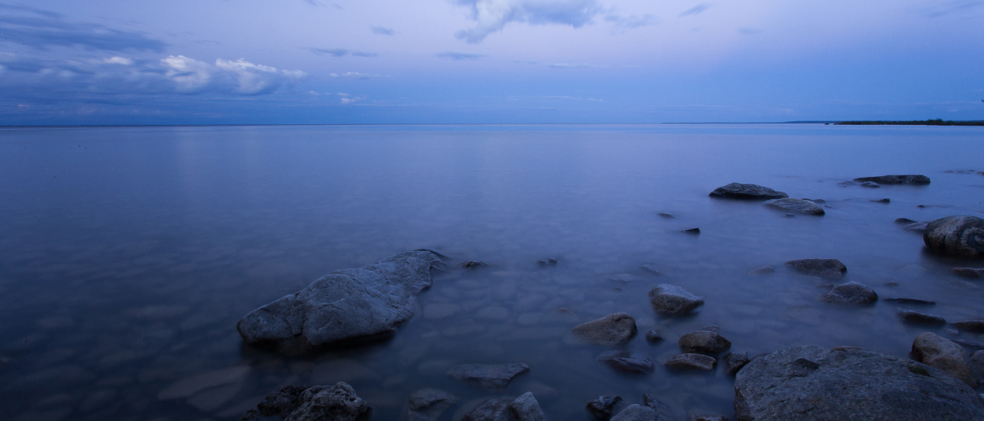 A lake at twilight with rocks in the foreground