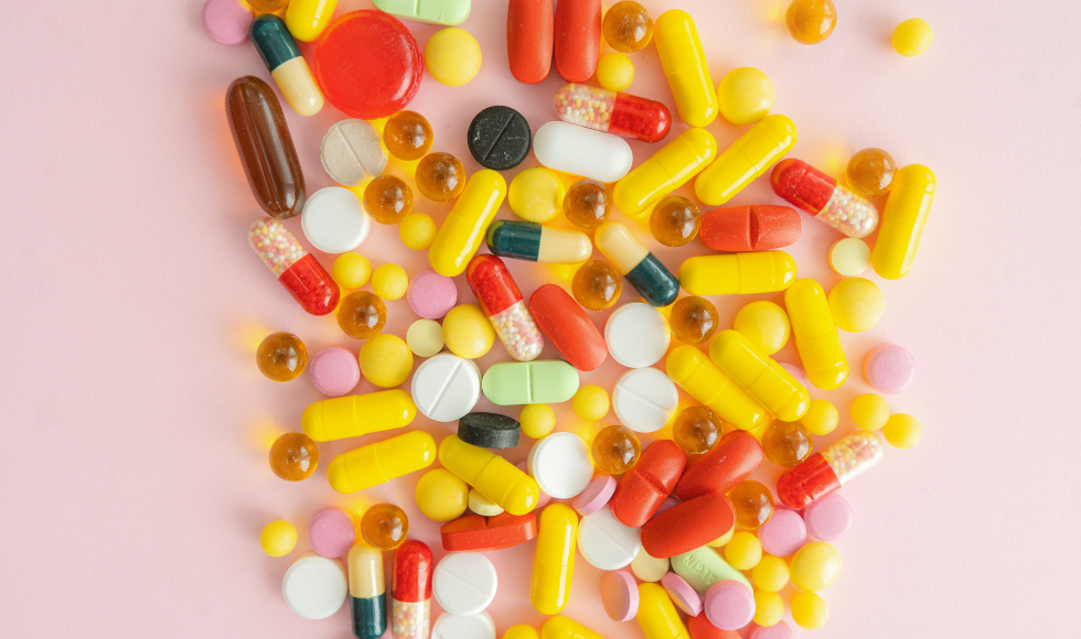A photo of a variety of pills on a pick backdrop