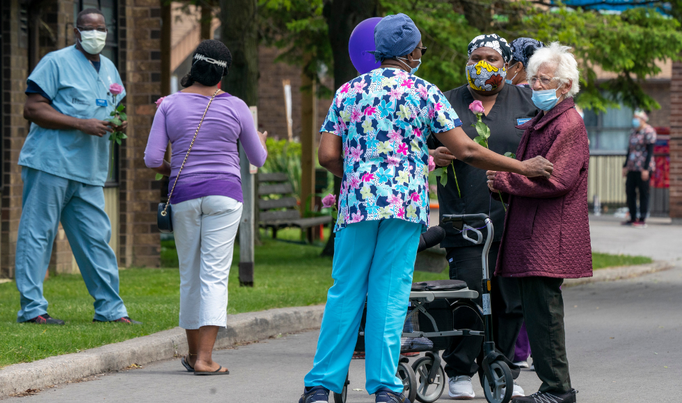 Long-term care home workers and residents chat outdoors