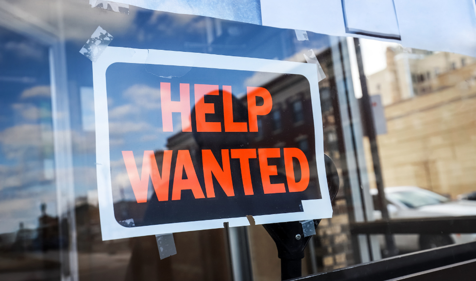 A "help wanted" sign in a store window