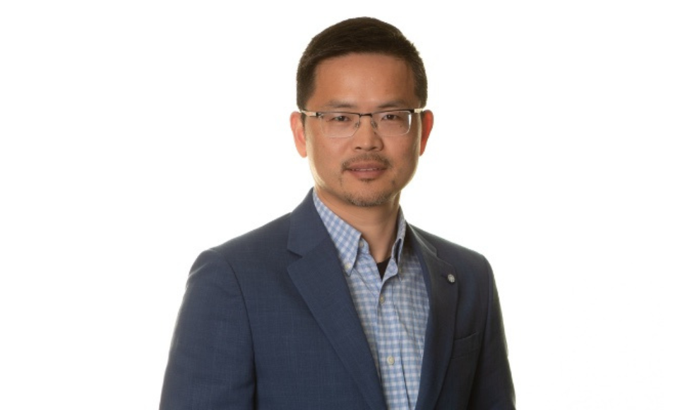 A headshot of Feng Xie. He is wearing a blue shirt, blue suit jacket, glasses and looking at the camera.